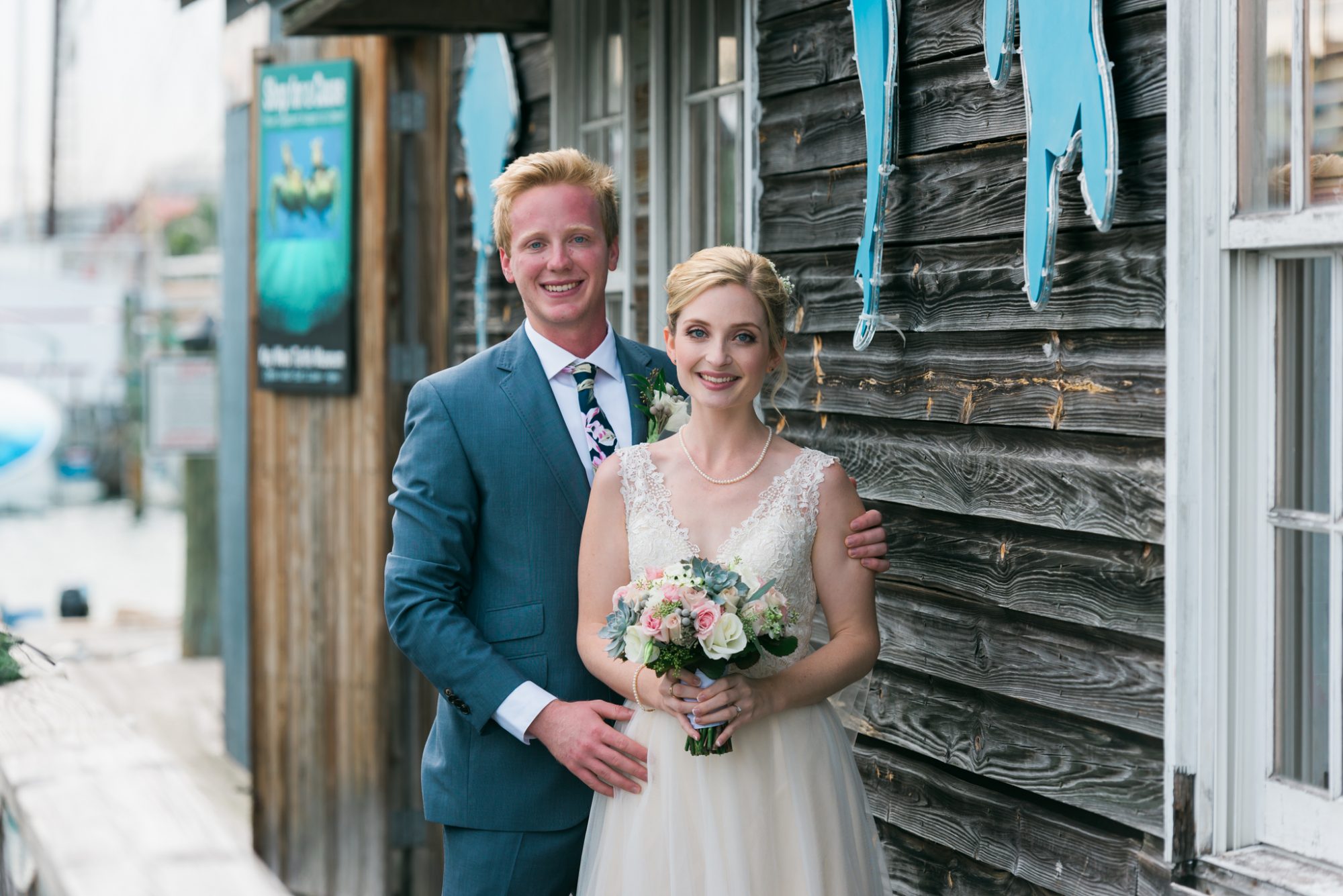 A bride and groom standing in front of a wooden building during their sailing themed Key West wedding.