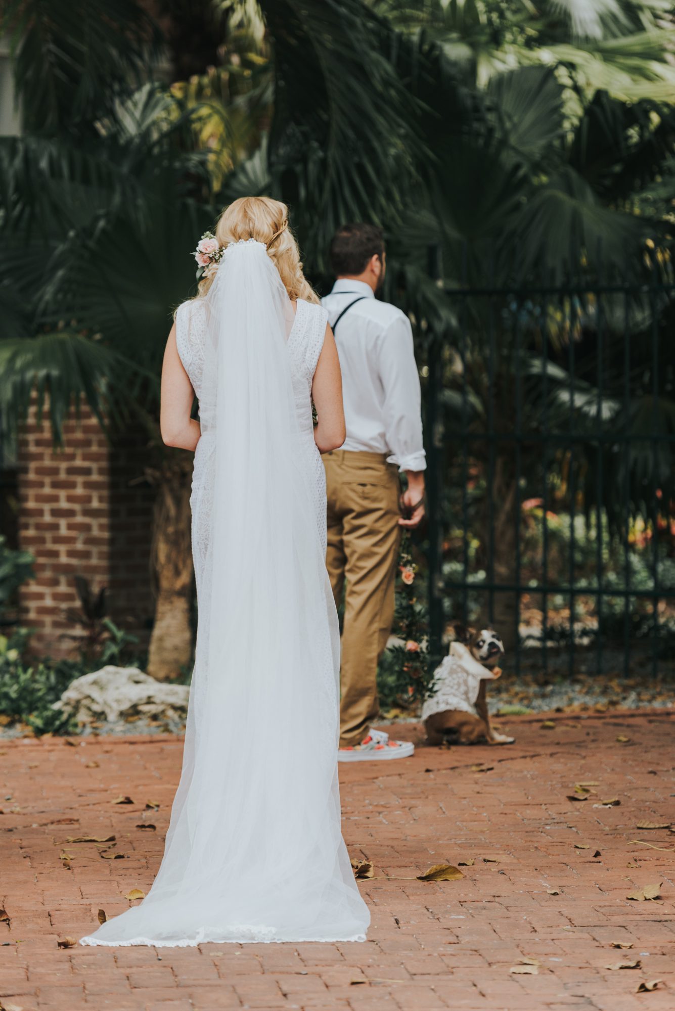 Amy and Teddy, a bride and groom, walking down a brick walkway at their Key West wedding.