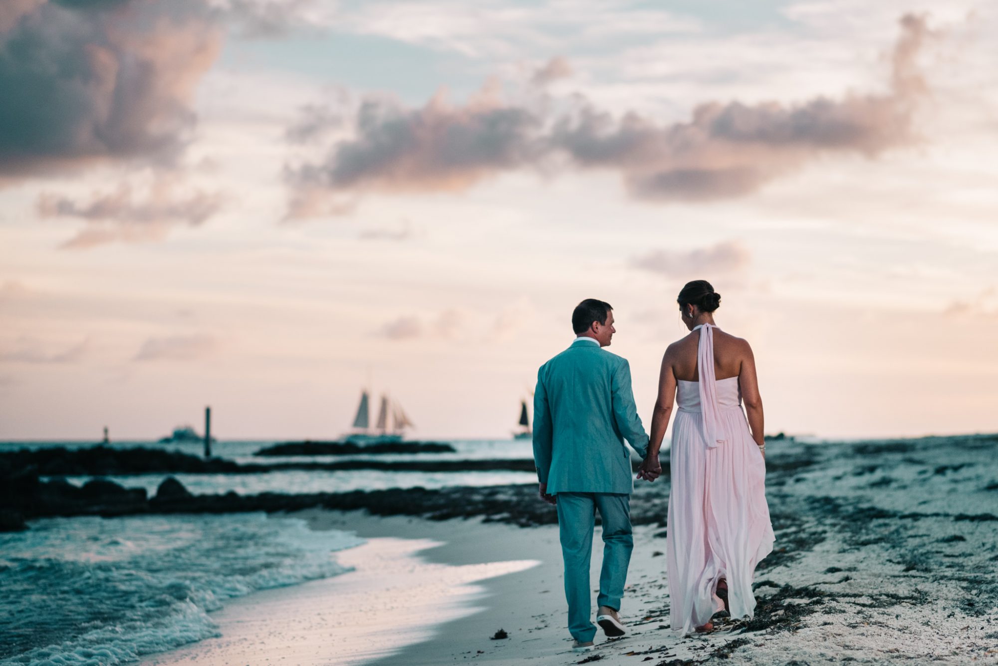 Freya and Jamie's Key West wedding: A bride and groom walking on the beach at sunset.