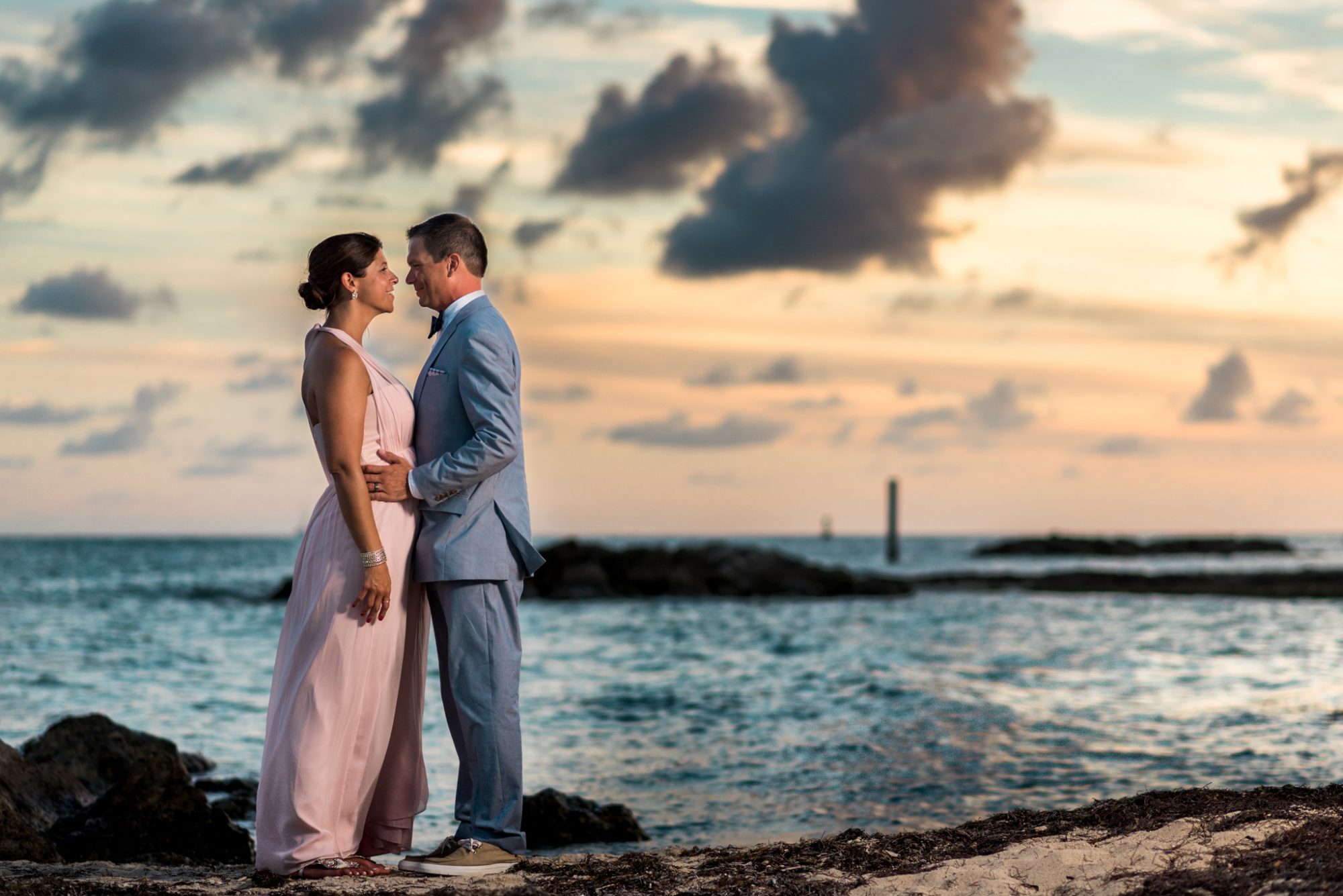 Freya and Jamie, a bride and groom, standing on a rock in Key West for their wedding ceremony.