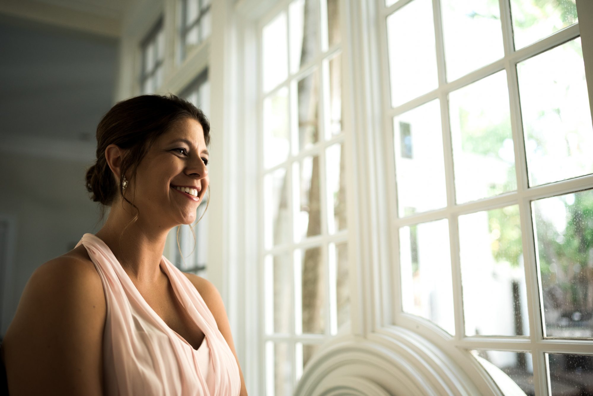 Freya smiling in front of a window at her Key West wedding.