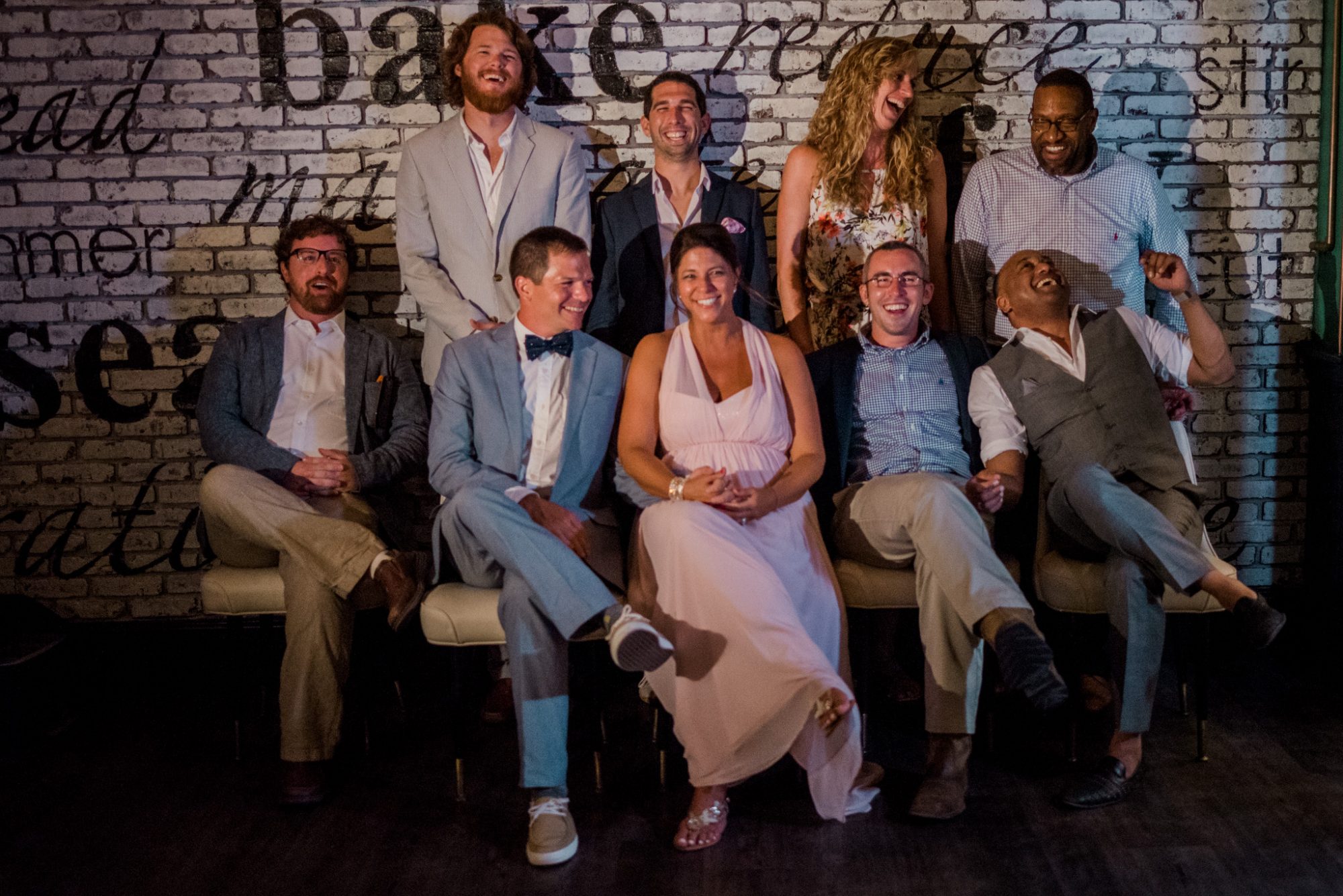 A group of people posing for a photo in front of a brick wall at a Key West Wedding.