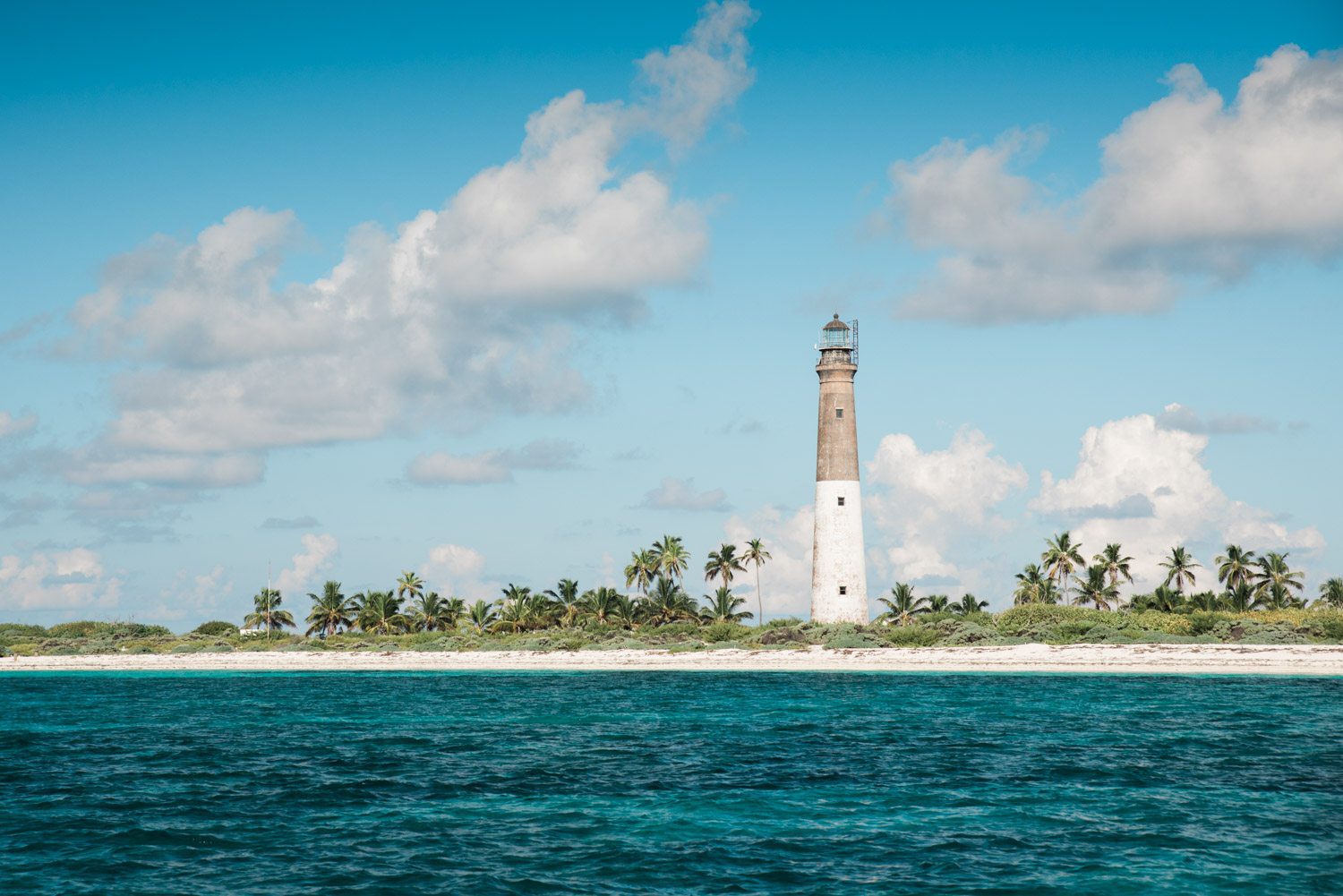 A dry tortugas lighthouse sits on a small island in the ocean, making it the perfect destination for an engagement session.