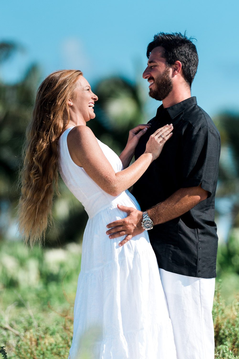 A man and woman are standing in a field together during their destination engagement session.