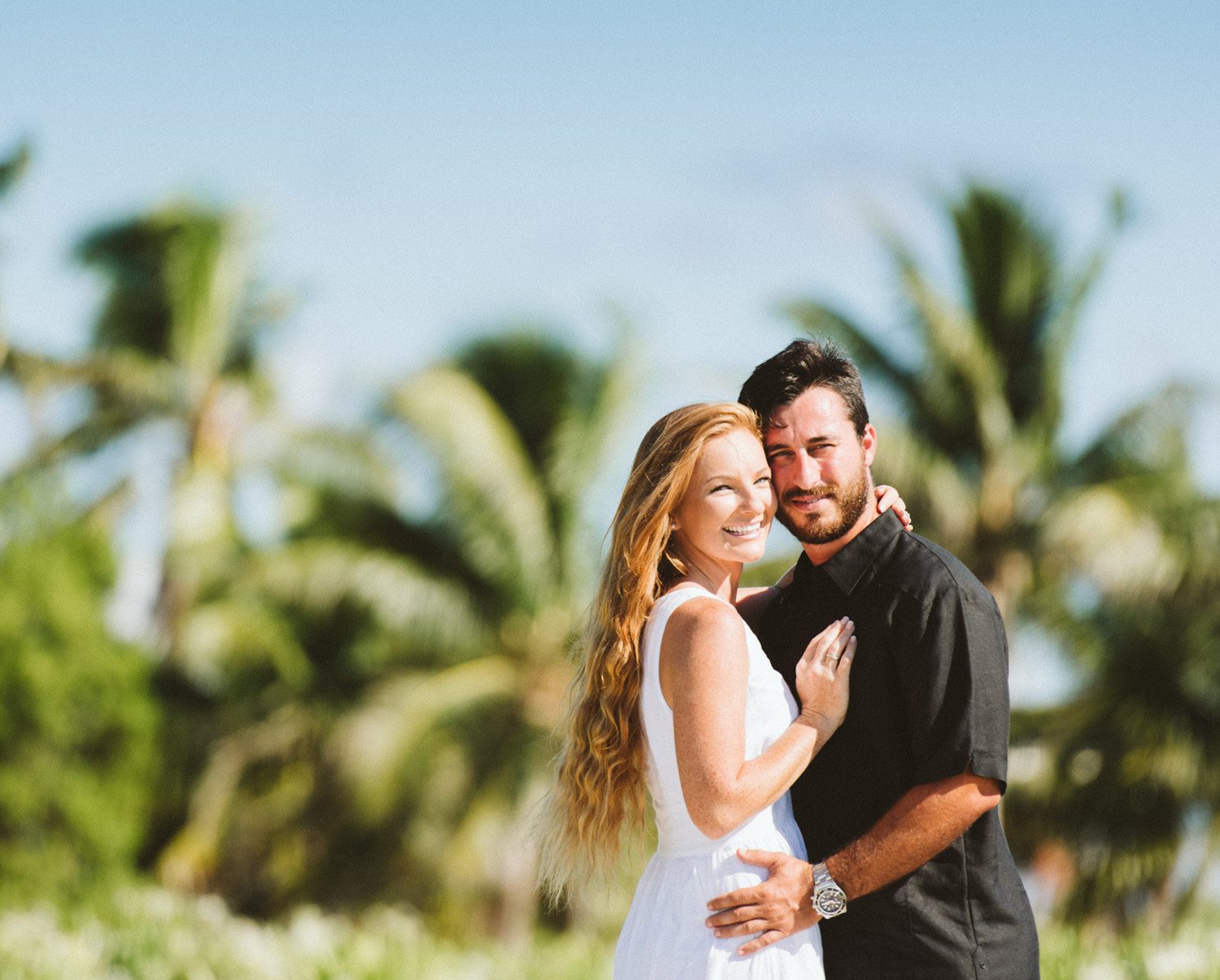 A couple posing for a destination engagement session photo in front of palm trees at Dry Tortugas.