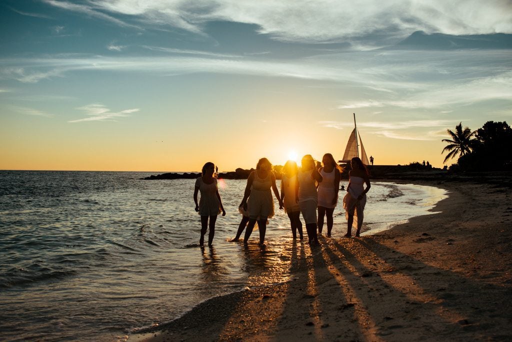 A group of women are walking on the beach at sunset during their bachelorette party weekend in Key West.