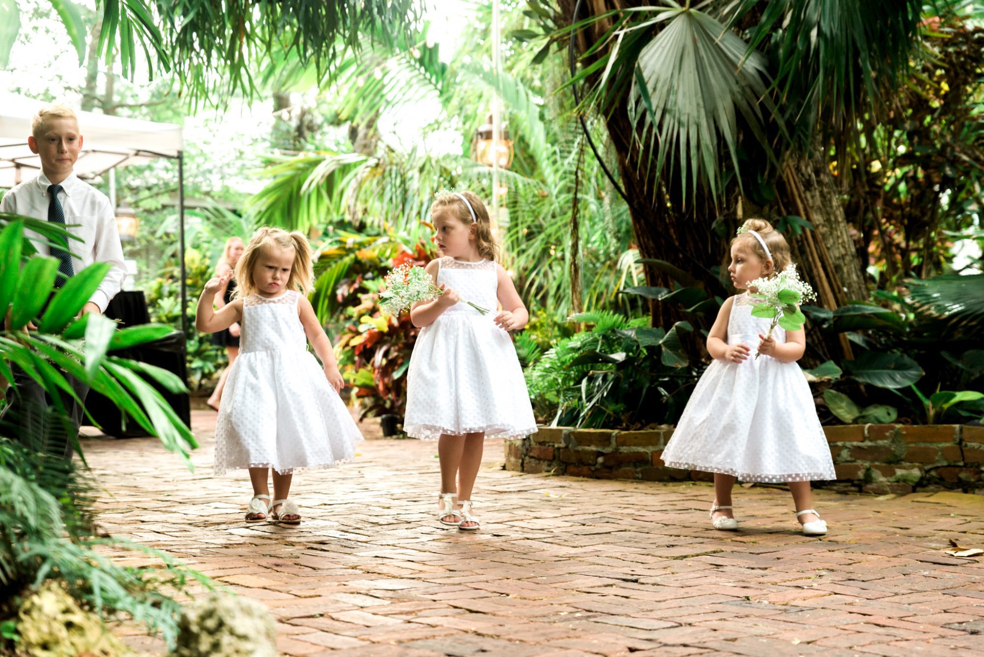 A group of girls in white dresses walking through the tropical garden at the Key West Audubon House and Gardens wedding.