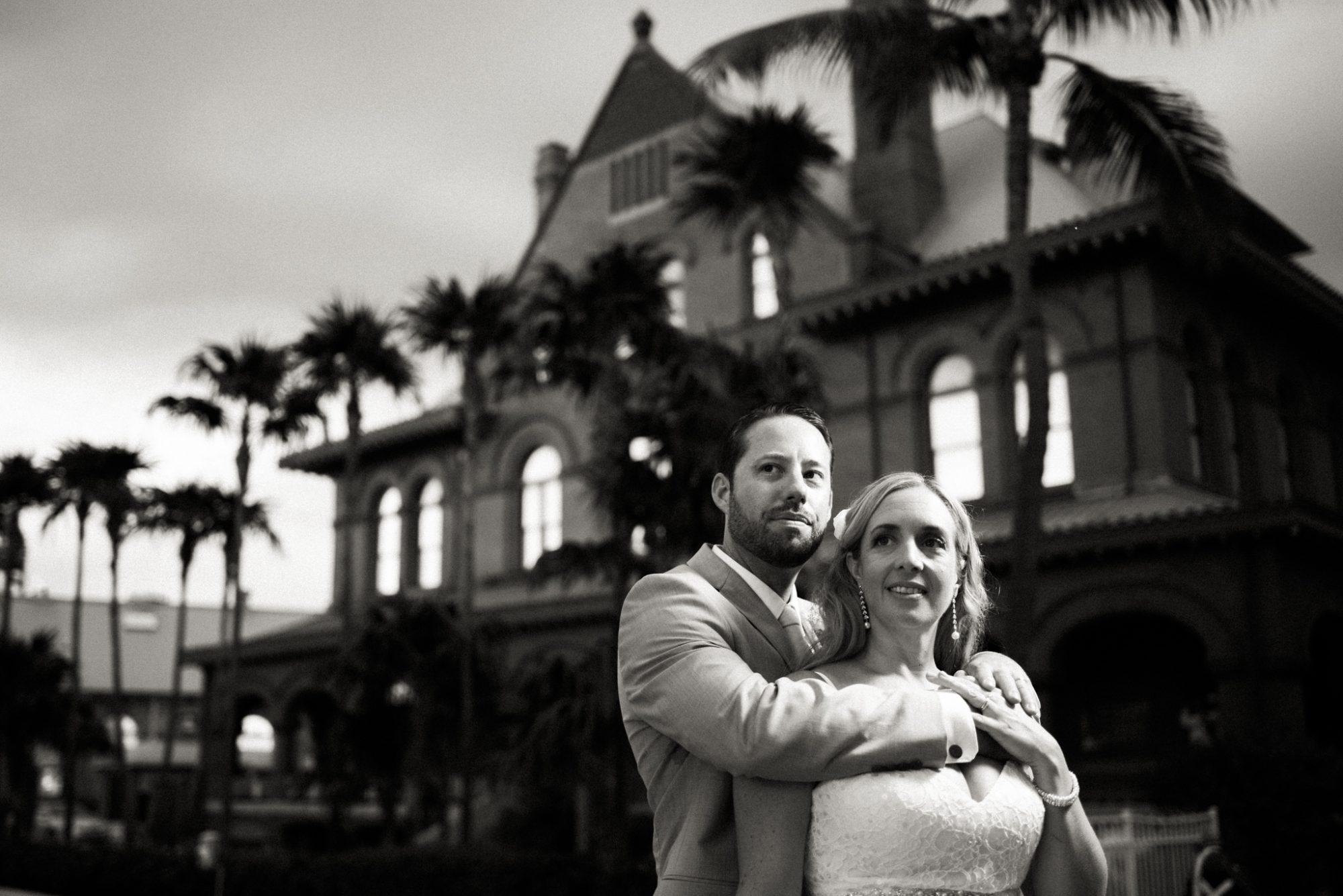 A bride and groom embracing in front of the Key West Audubon House and Gardens.