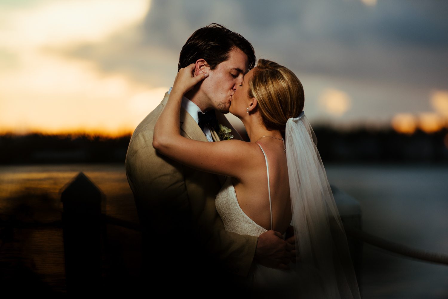 A bride and groom share a romantic kiss in front of the water at sunset during their Key West wedding.