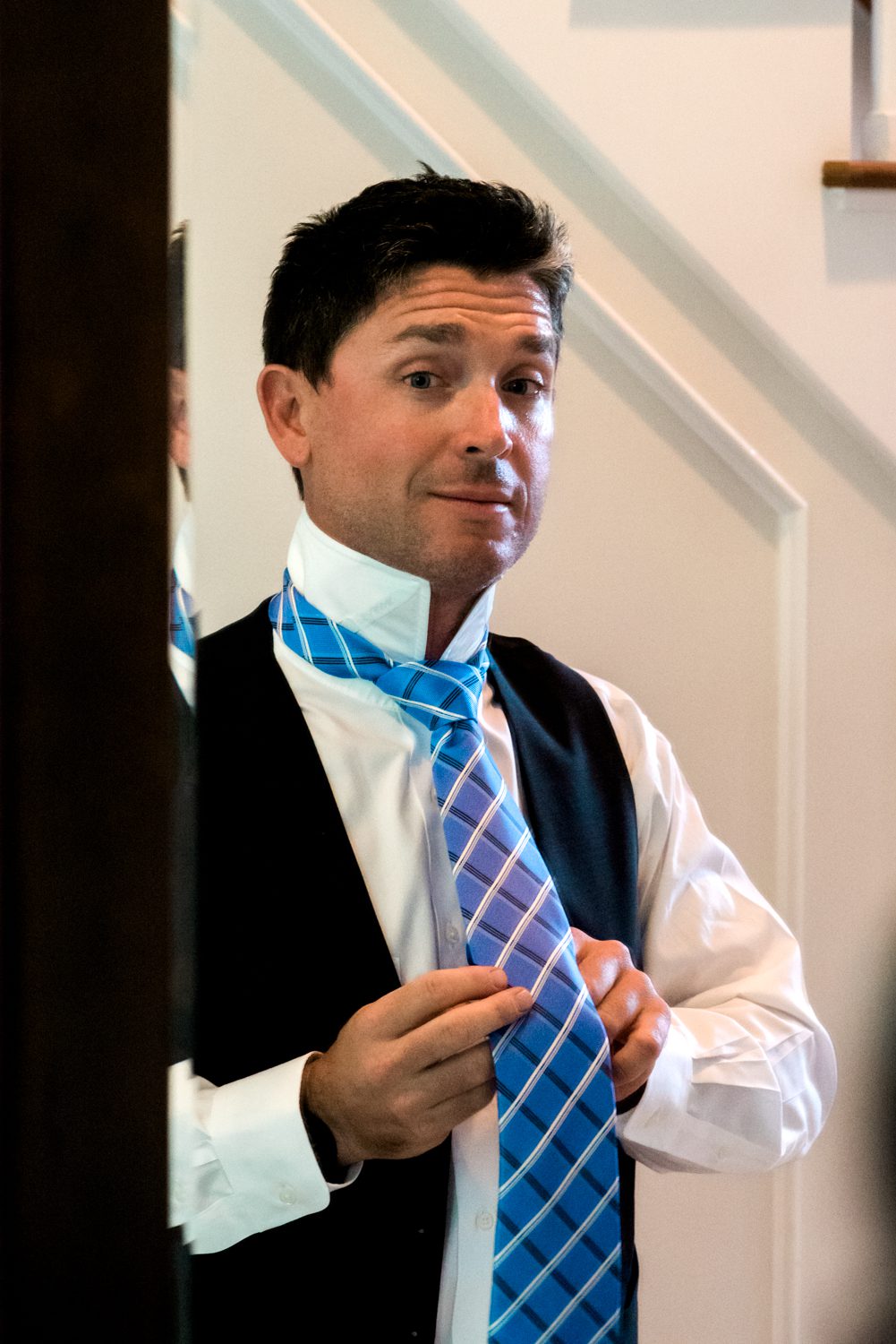 A man elegantly donning a tie at a Key West Garden Club wedding.