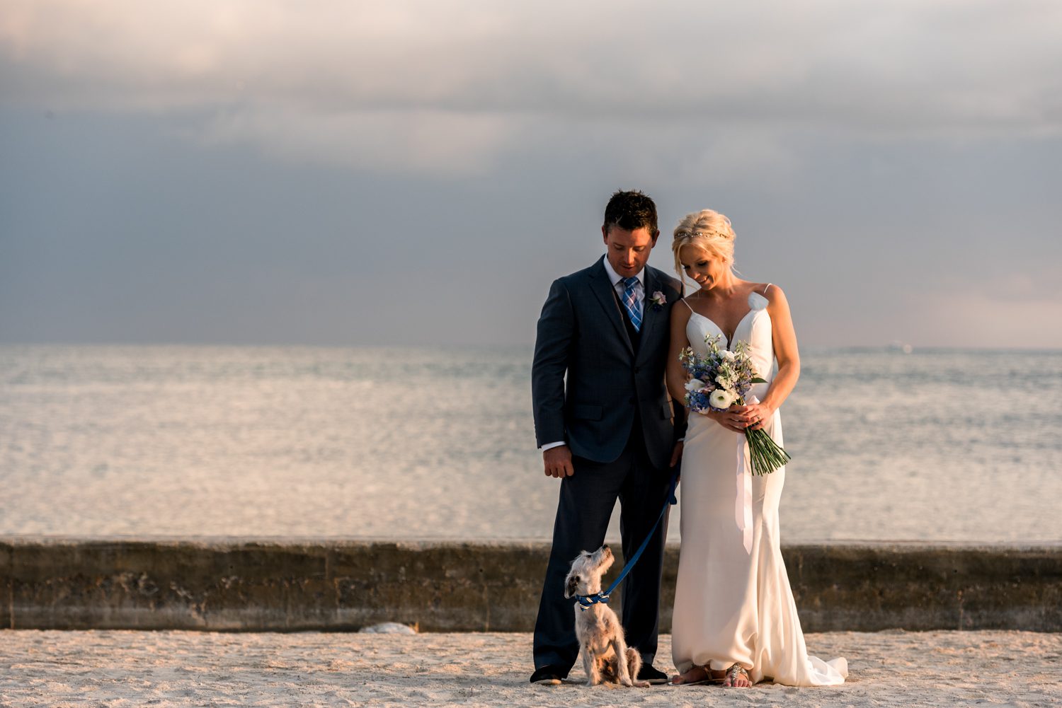 A beautiful bride and groom exchange vows on the sandy beaches of Key West Garden Club, accompanied by their beloved dog.
