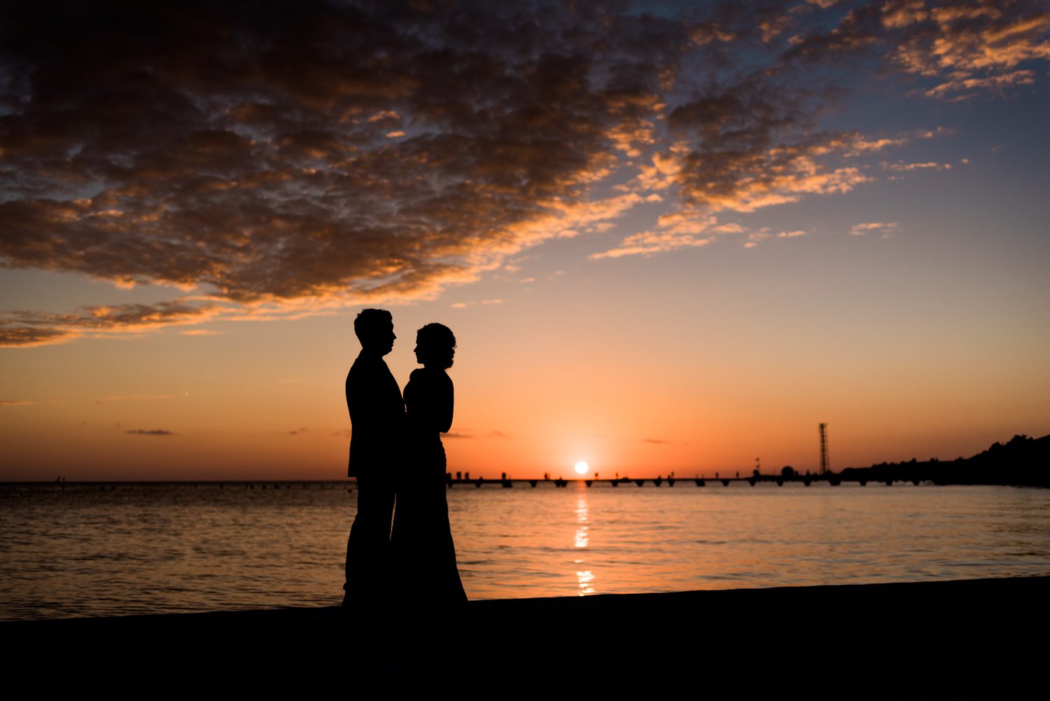 A silhouette of a couple standing on the beach at sunset, capturing the romantic ambiance of a Key West garden club wedding.