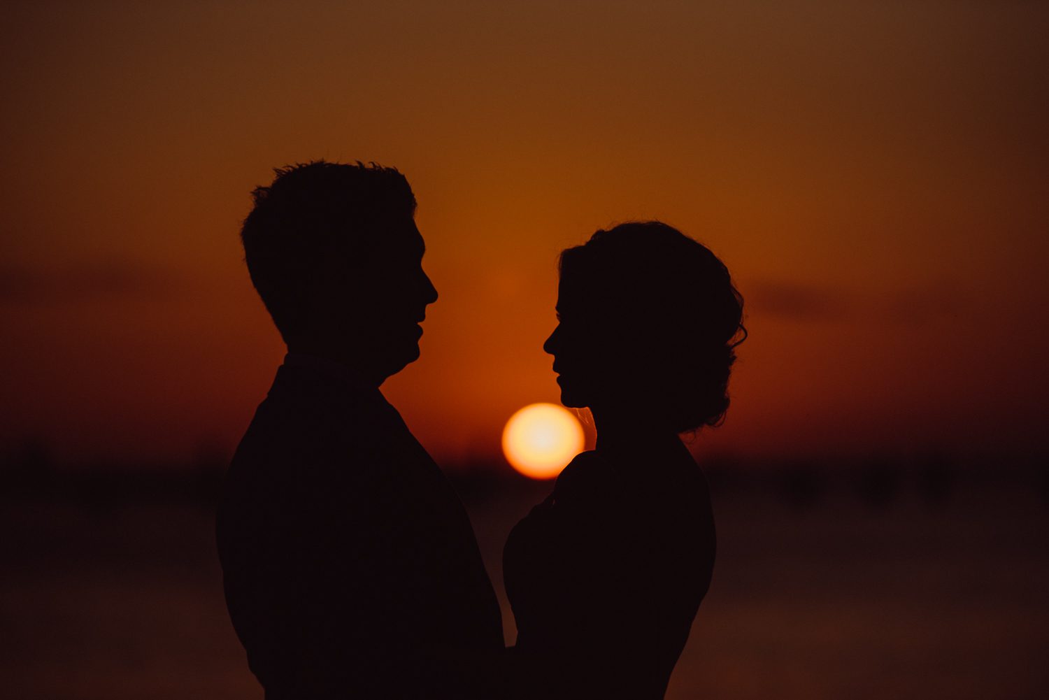 A silhouette of a couple standing in front of a sunset at their Key West Garden Club wedding.