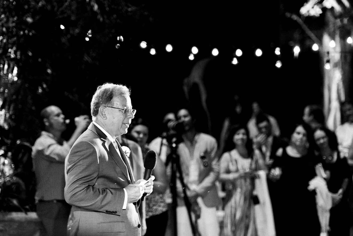 A black and white photo of a man giving a speech at a Key West Garden Club wedding.