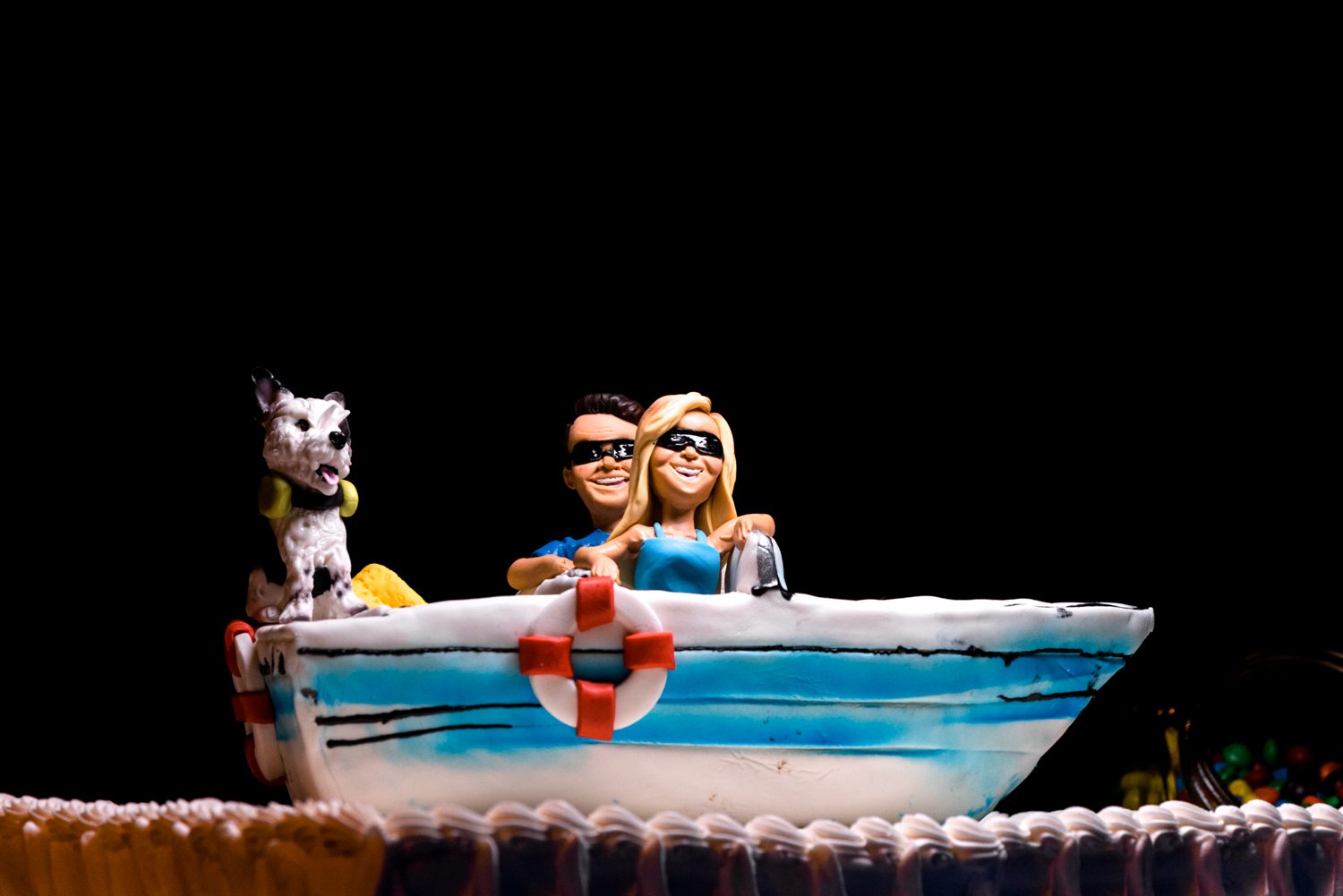 A cake with a couple and a dog in a boat, perfect for Key West garden club weddings.