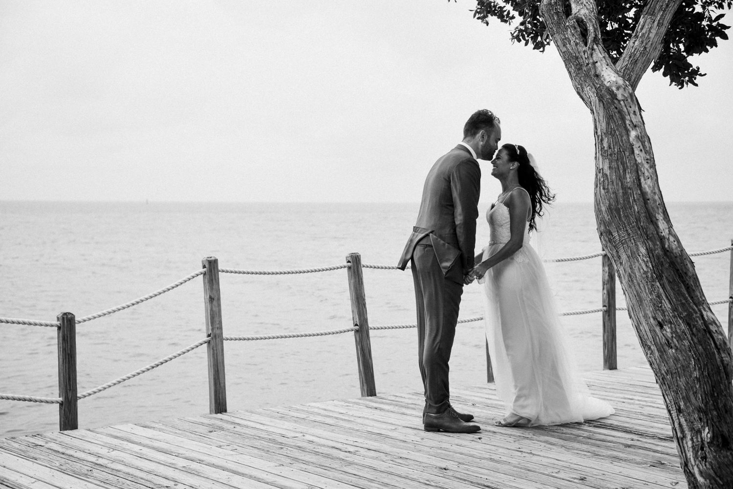 A bride and groom share a romantic kiss on a dock overlooking the ocean at their Florida Keys wedding at Postcard Inn.