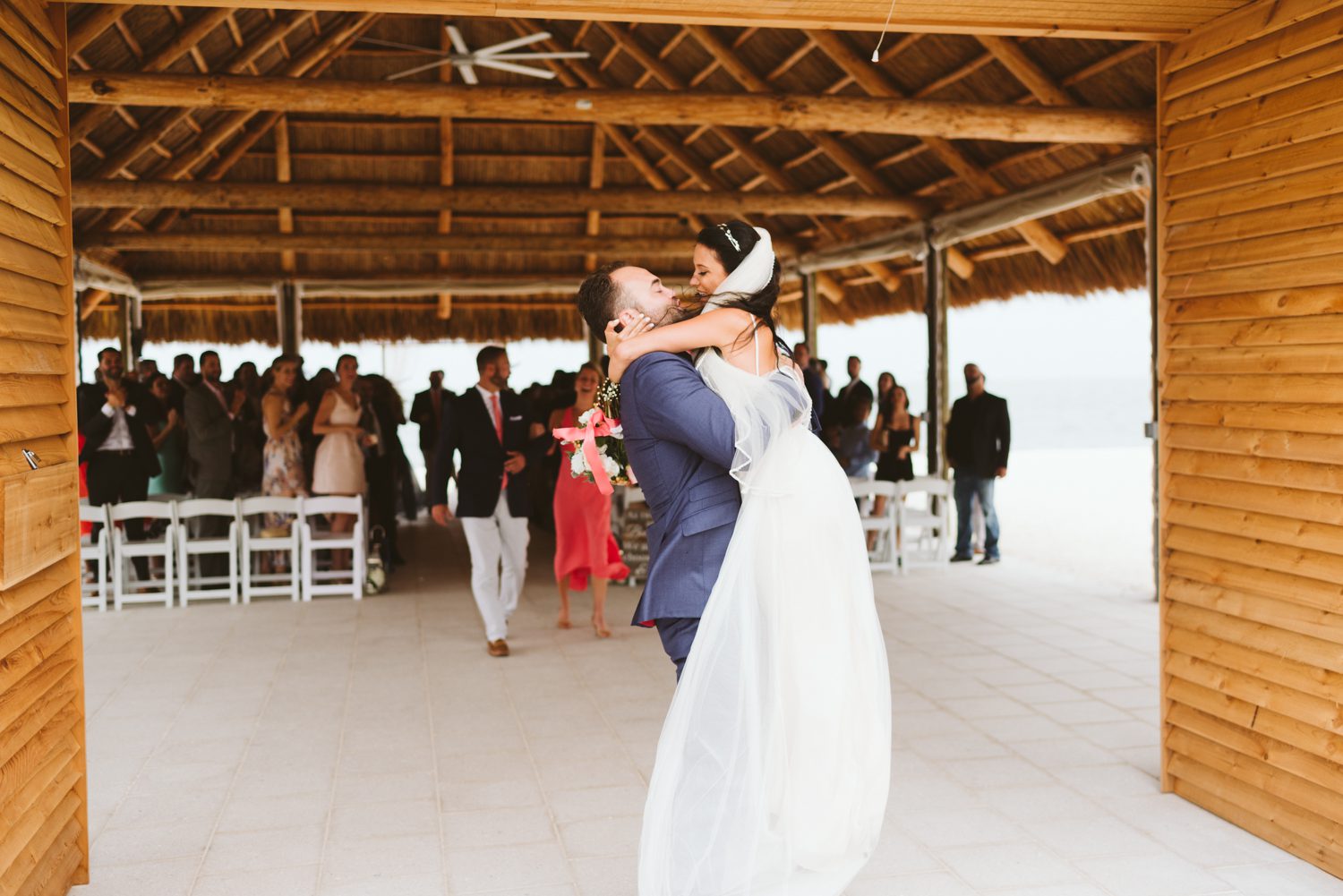 A bride and groom hugging in front of a picturesque gazebo at their Florida Keys wedding.