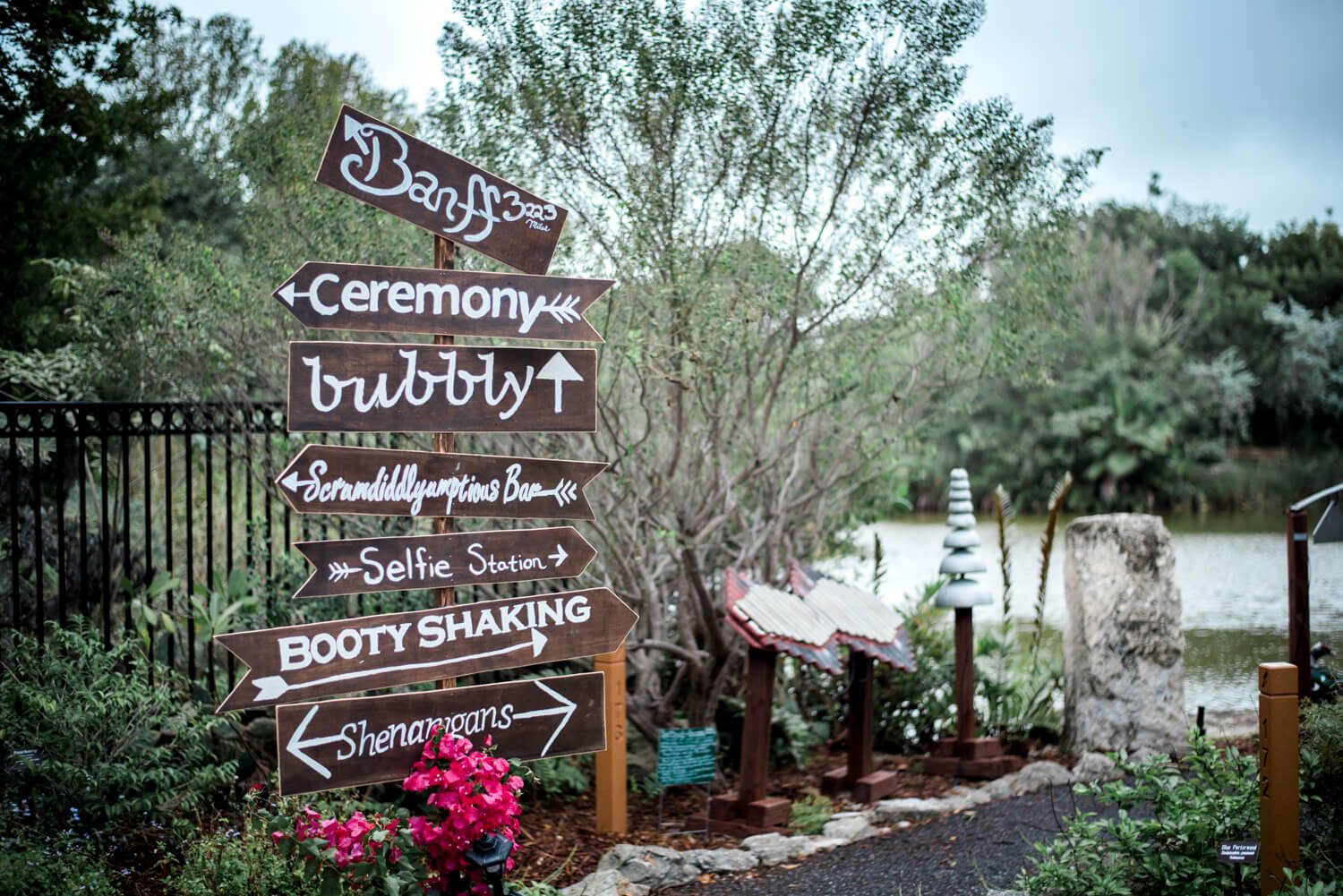 A wooden sign with arrows in front of a fence at a Key West wedding photographed by Freas Photography.