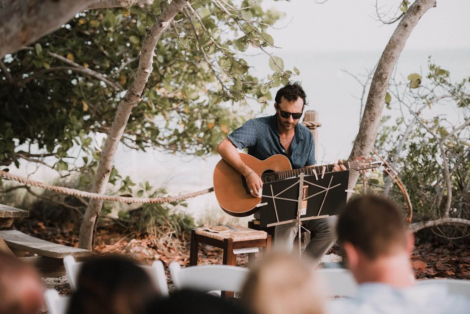 A man playing an acoustic guitar at a Kristina & Forrest outdoor wedding in Key West, captured by a Fort Zachary Taylor photographer.