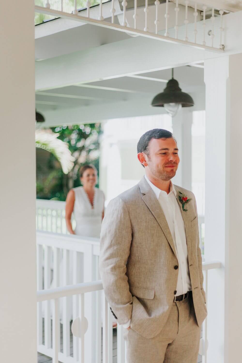 A groom at Ocean Key Resort Spa Wedding in Key West, standing on a porch in a tan suit.