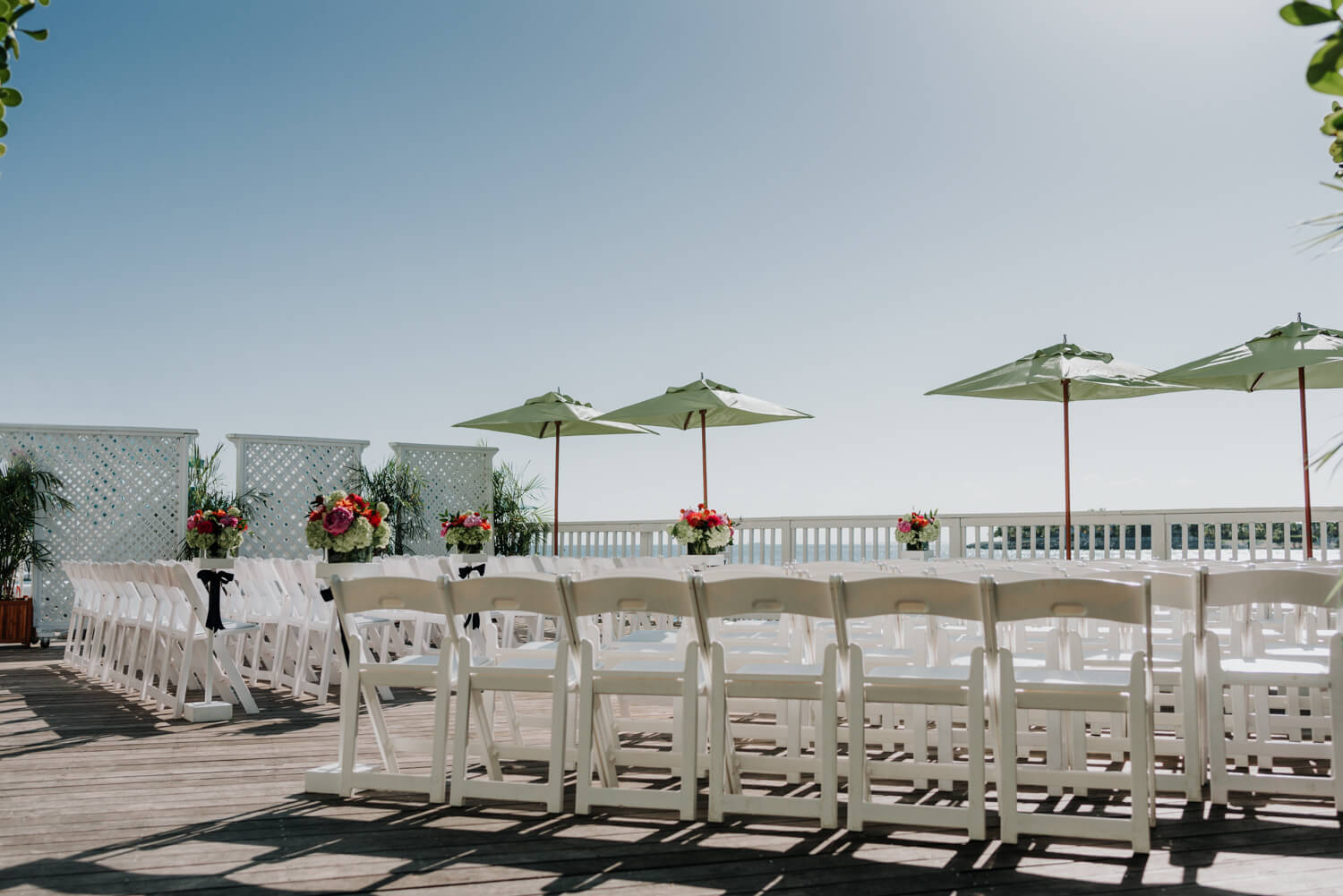 An Ocean Key Resort Spa wedding ceremony with white chairs and umbrellas.