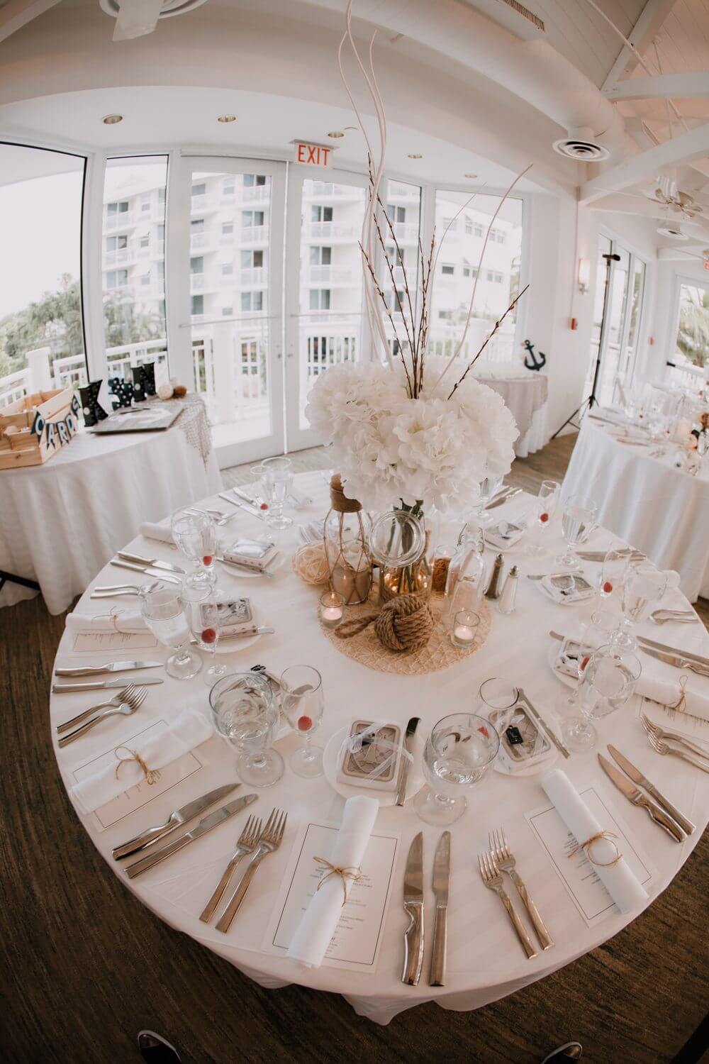 A Key West wedding reception table set up with white linens and silverware.