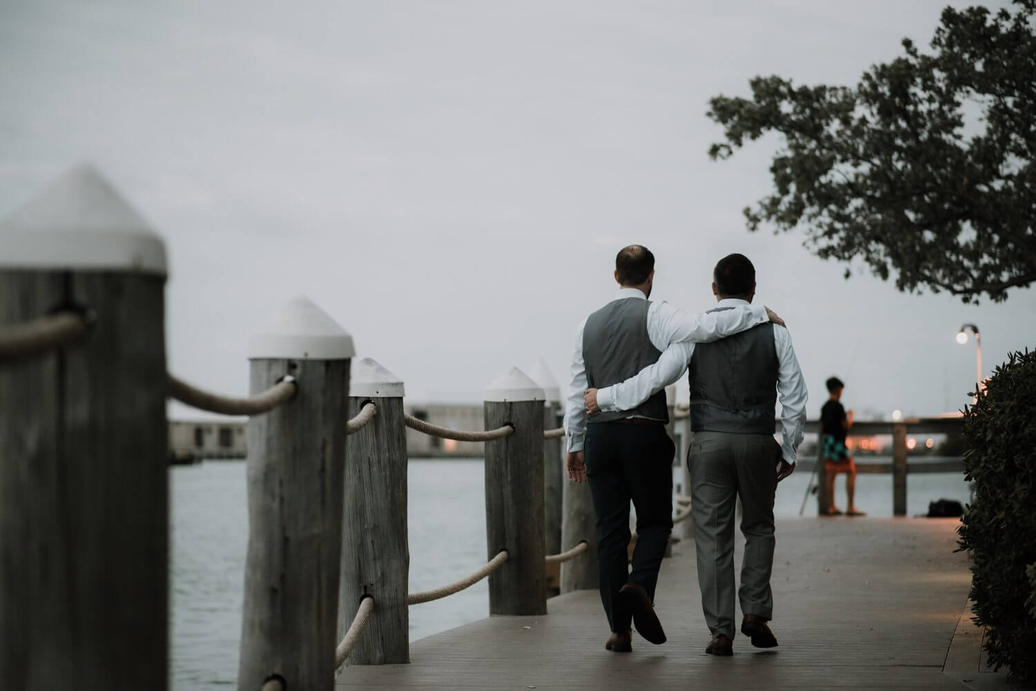 Two grooms having a Key West wedding at Hyatt Centric Resort, walking down a dock at night.