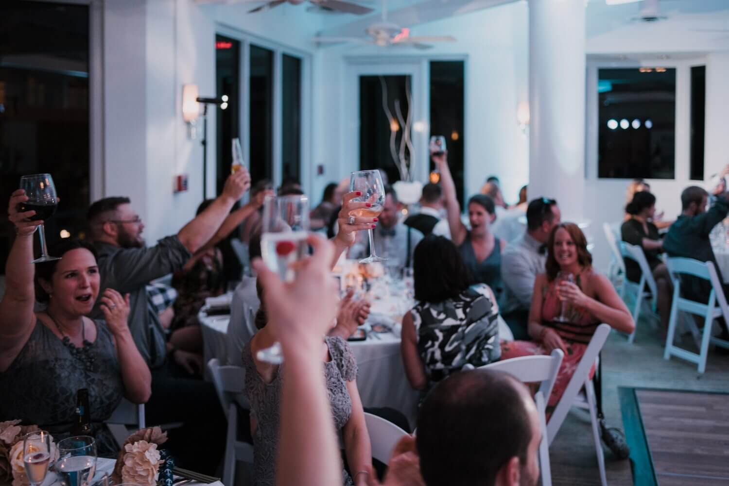 A group of people raising their glasses at a Key West wedding reception.