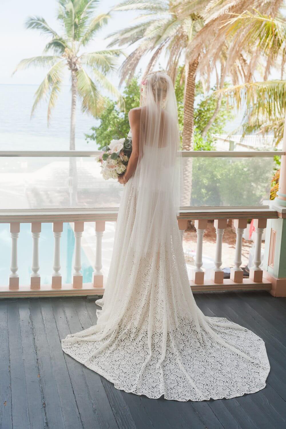 A bride is standing on a balcony at the Southernmost Mansion in Key West, overlooking the ocean.