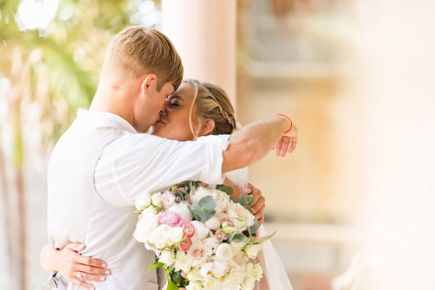 A bride and groom hugging in front of the Southernmost Mansion during their Key West wedding.