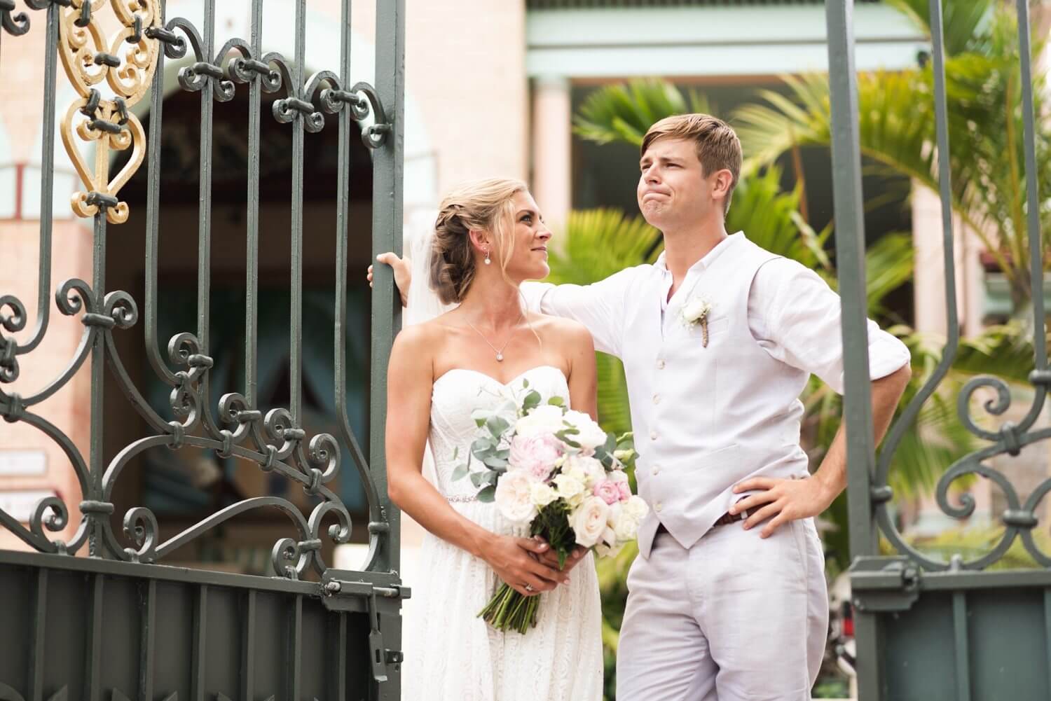 A bride and groom standing in front of the Southernmost Mansion's iron gate at their Key West wedding.