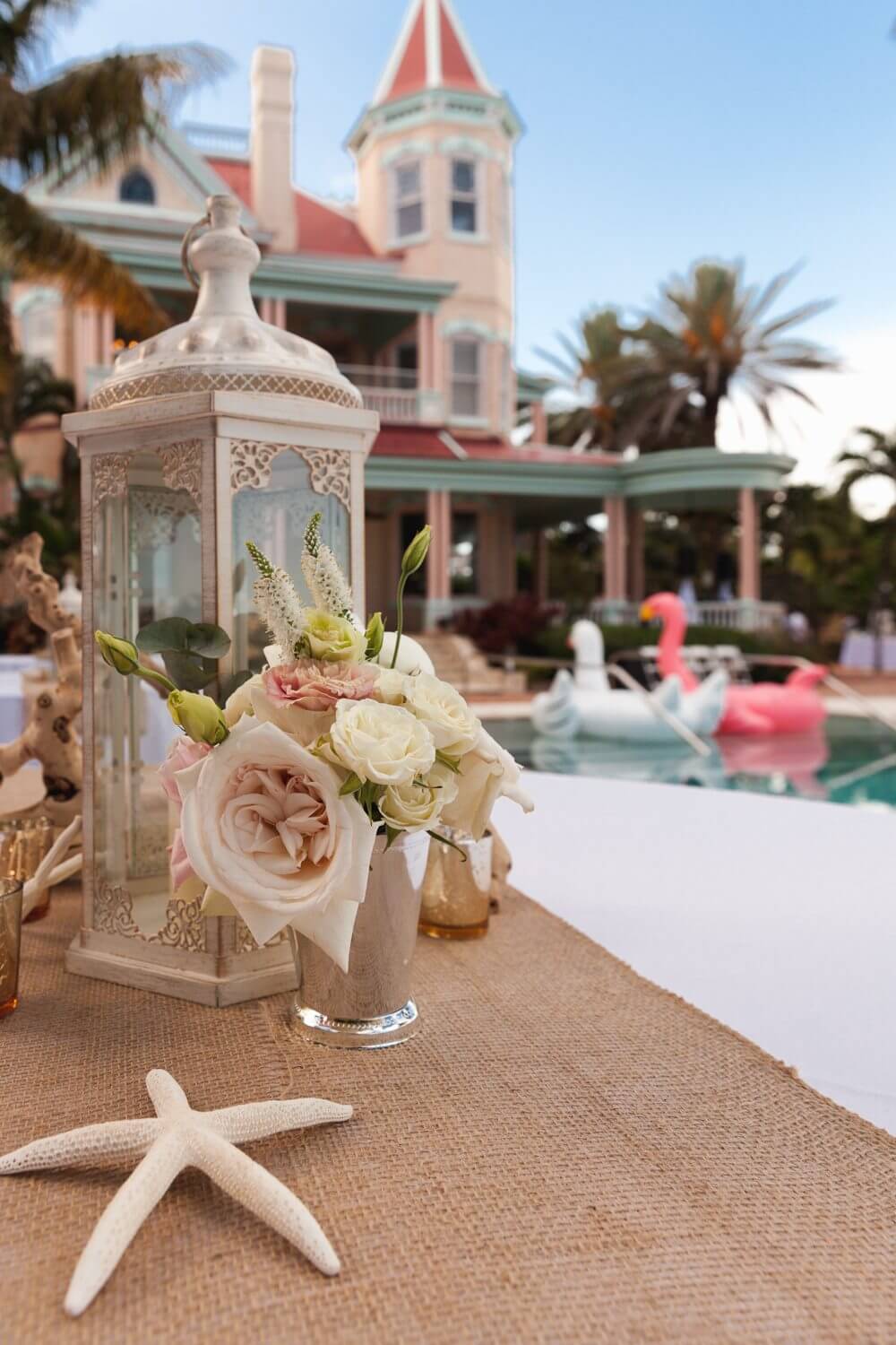 A table with flowers and a lantern next to a pool, perfect for a Key West wedding at the Southernmost Mansion.