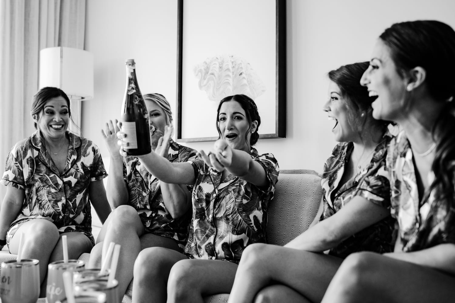 Bridesmaids at a Bakers Cay Resort wedding, laughing and holding a bottle of champagne.