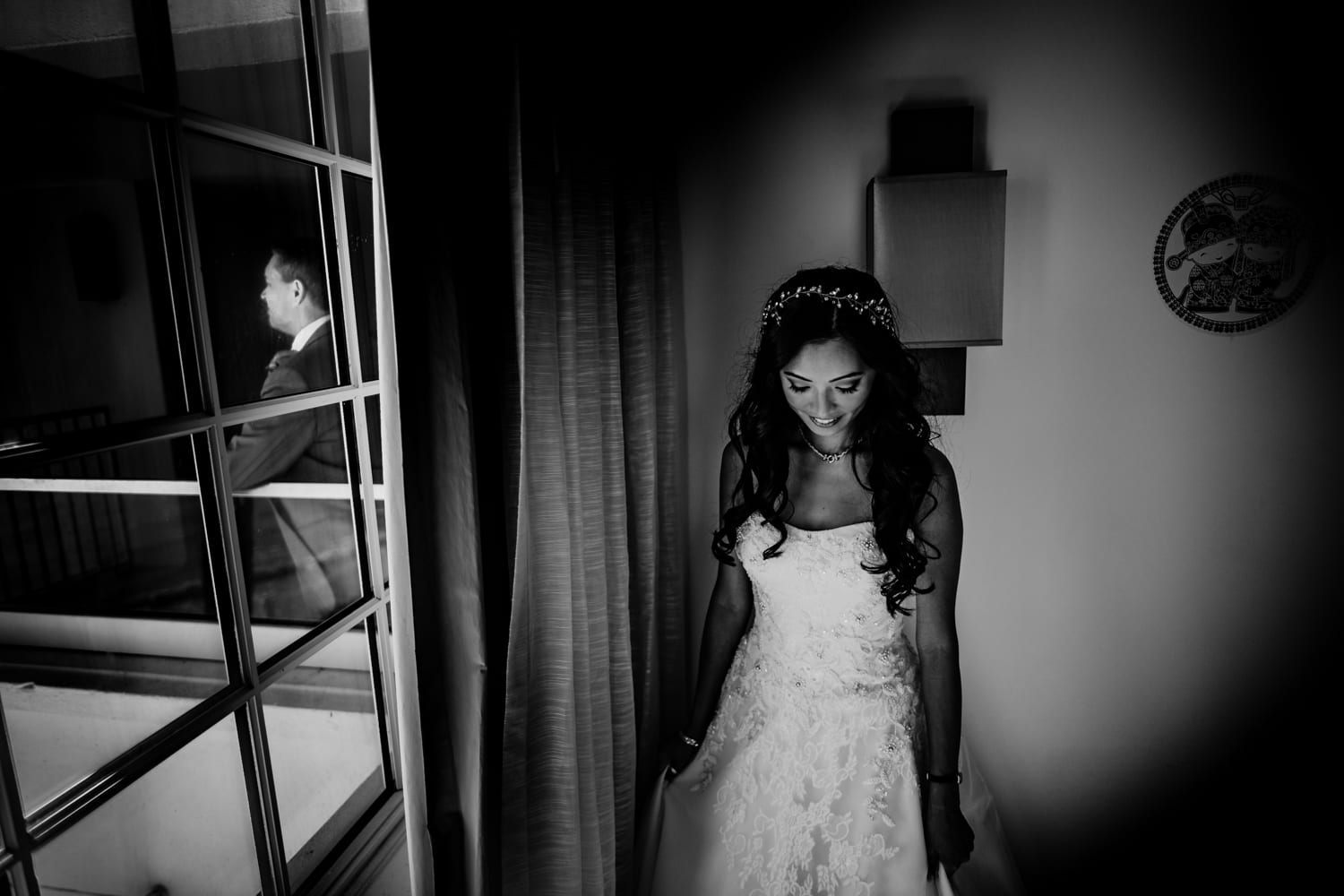 A bride in a wedding dress standing in front of a window.