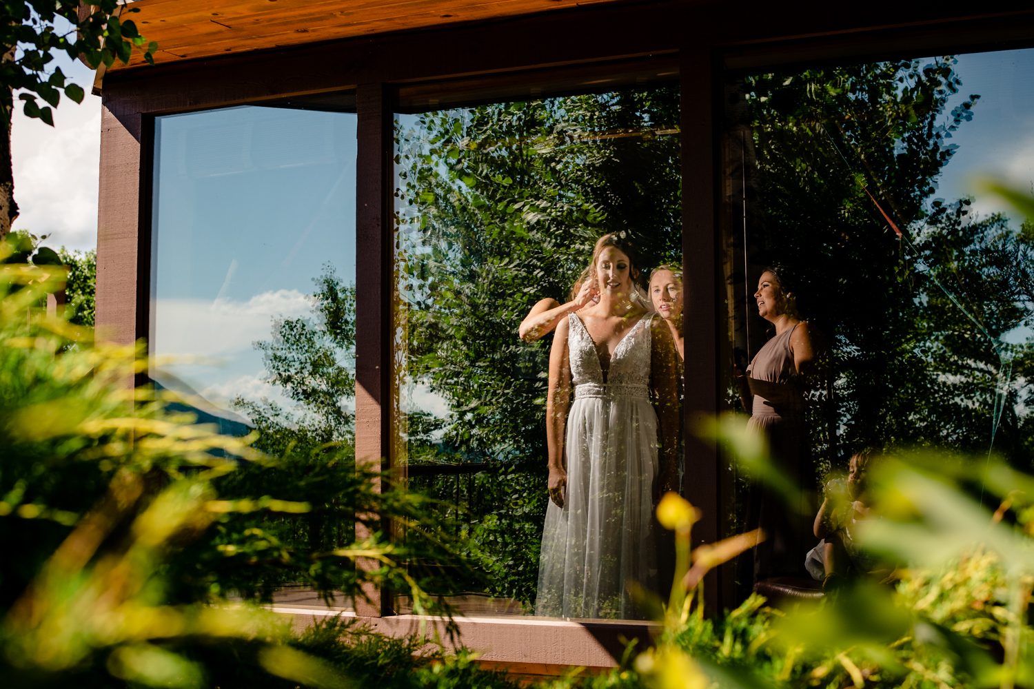 A bride and her bridesmaid standing in front of a glass door at a Steamboat Springs wedding.