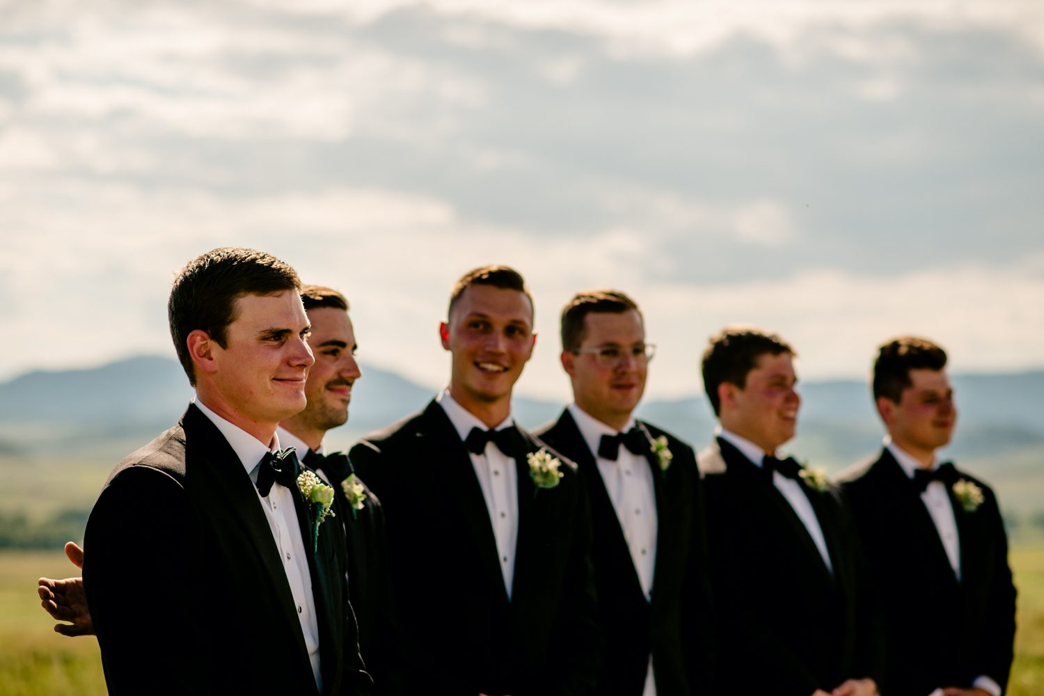 Groomsmen in tuxedos standing in a field at a Steamboat Springs wedding.