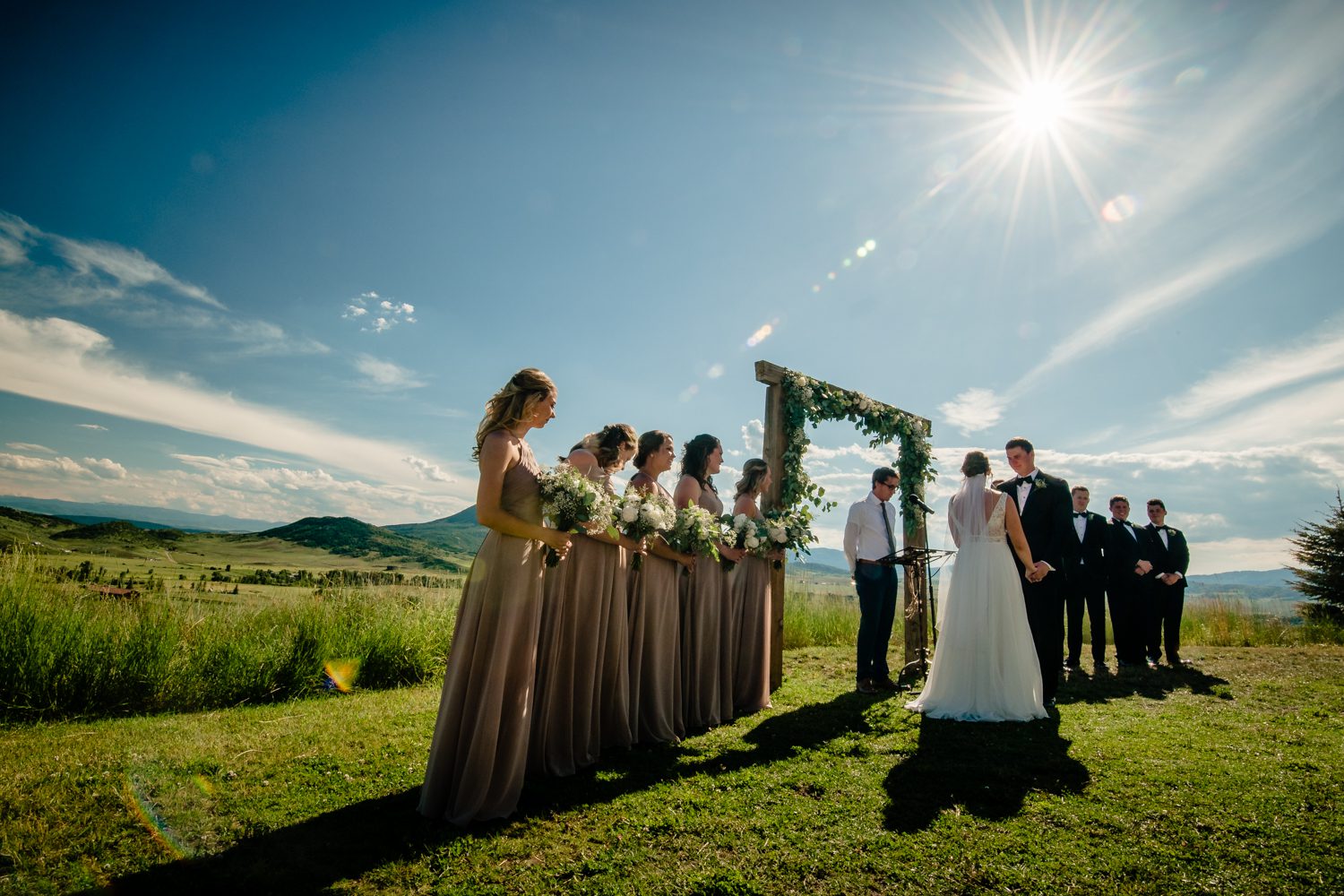 A bride and groom stand in front of the sun during their La Joya Dulce wedding ceremony.