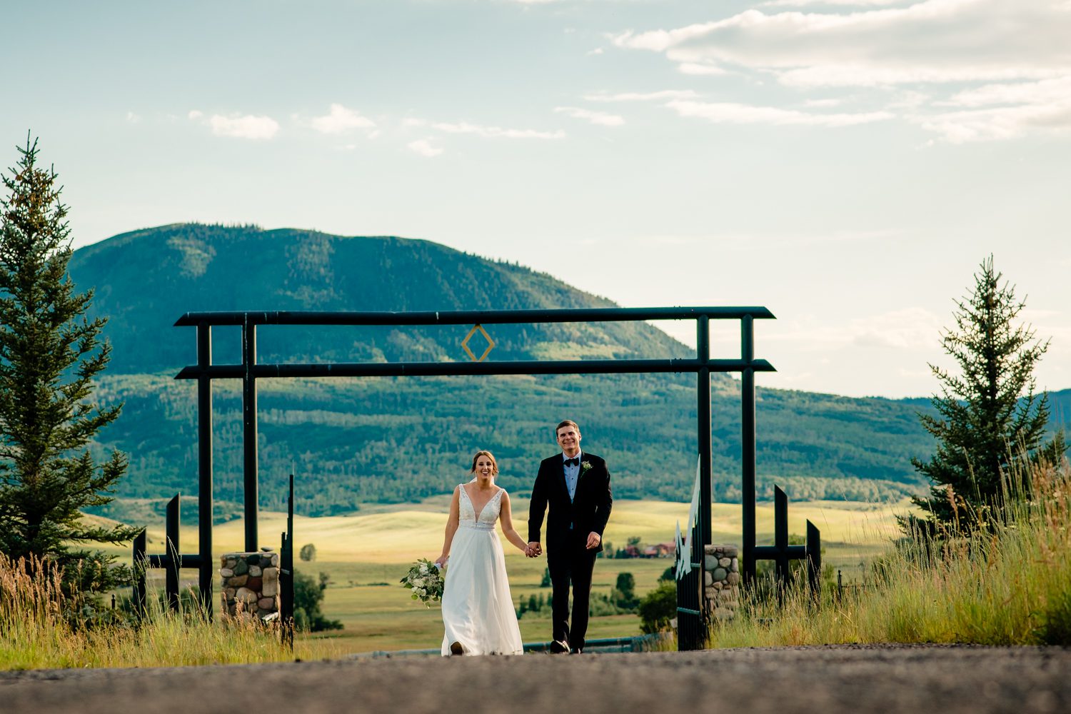 A bride and groom walking down a road with mountains in the background at a Steamboat Springs wedding.