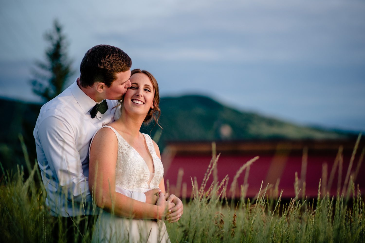 A bride and groom embrace in tall grass at a Steamboat Springs wedding.