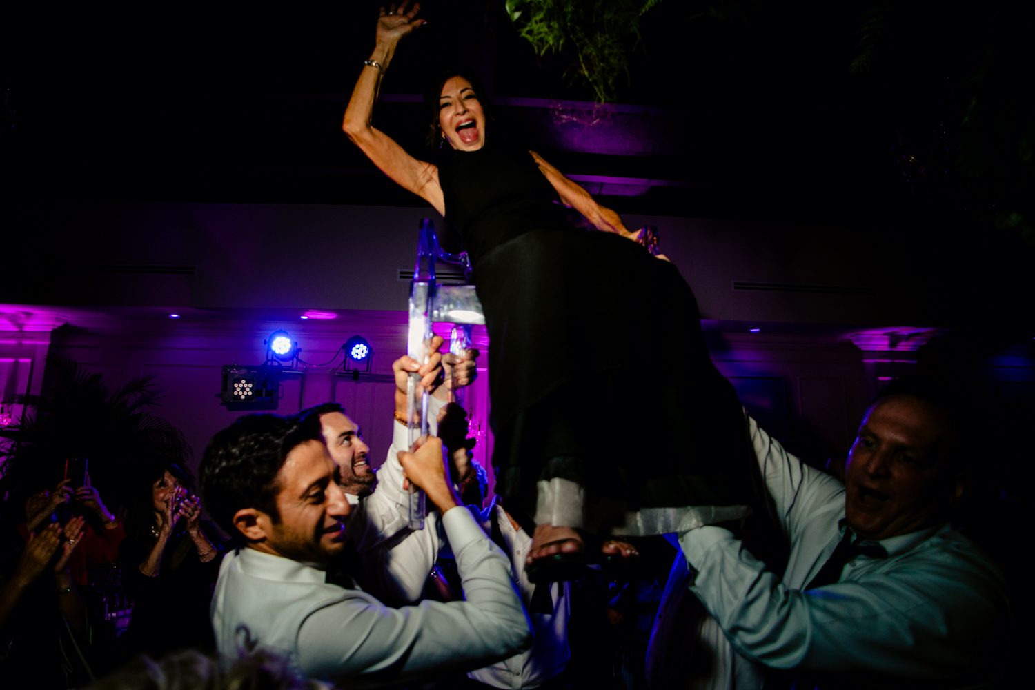 A woman is being carried by a man at a wedding.