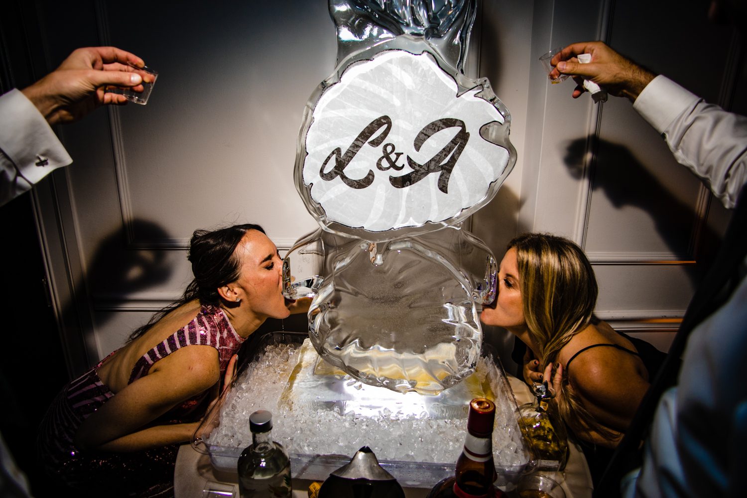 A group of people kissing in front of an ice sculpture at a Jewish wedding in Miami, FL.