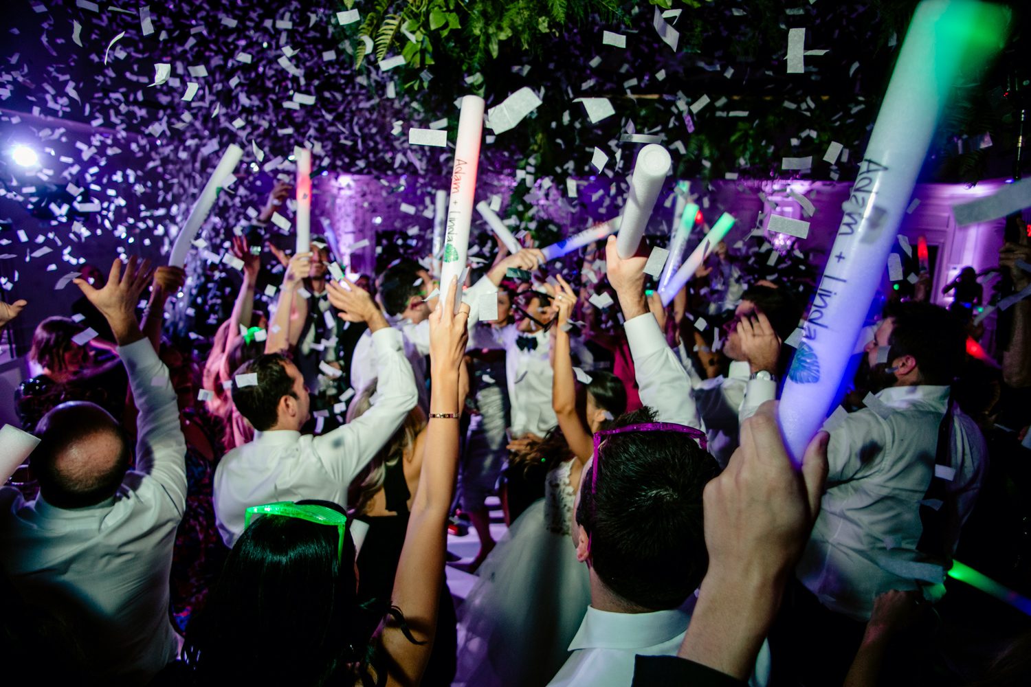A group of Jewish people holding confetti sticks at a wedding reception in Miami, FL.