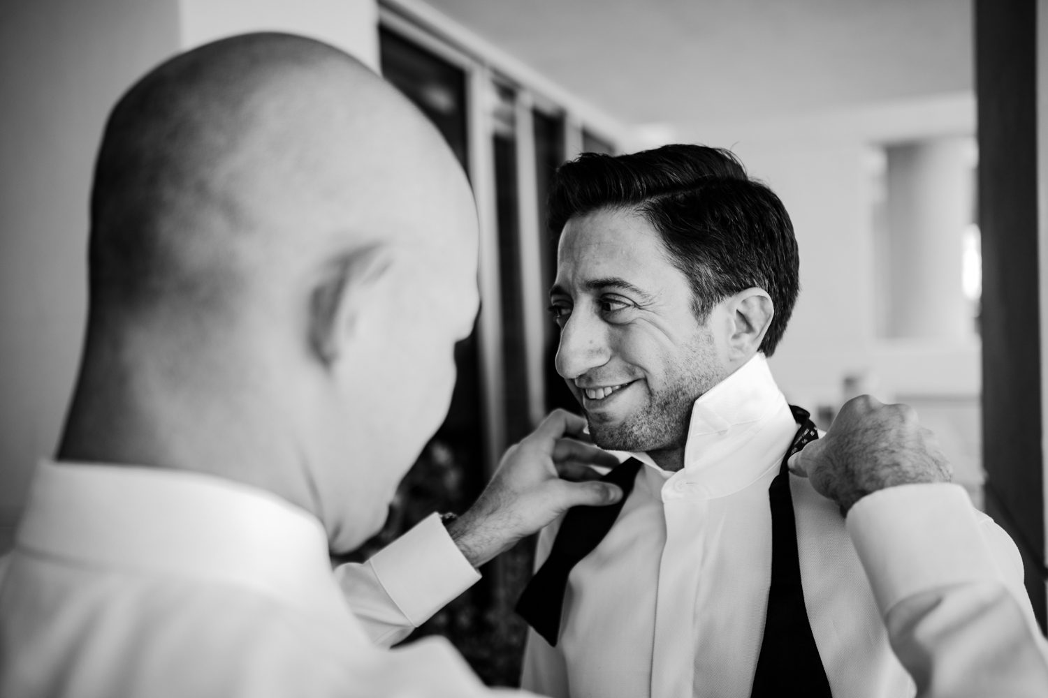 A man is tying his tie in a black and white photo.