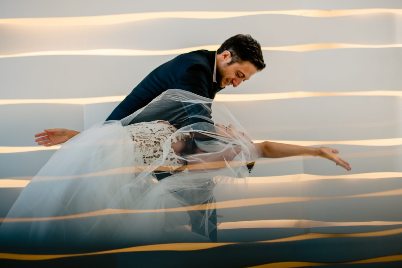 A modern bride and groom posing in front of a mirrored wall at a Jewish wedding in Miami.