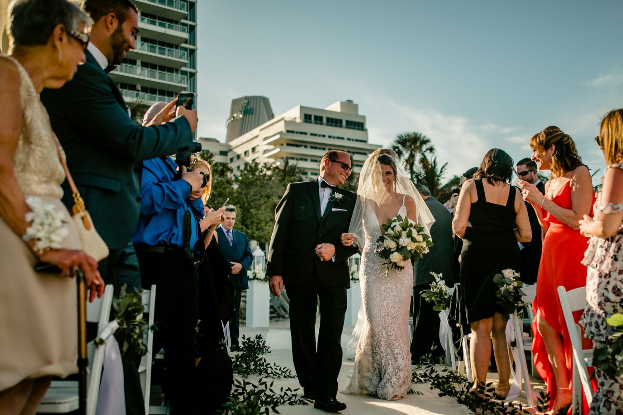 A bride and groom walking down the aisle at a wedding ceremony held at Eden Roc Resort in Miami.