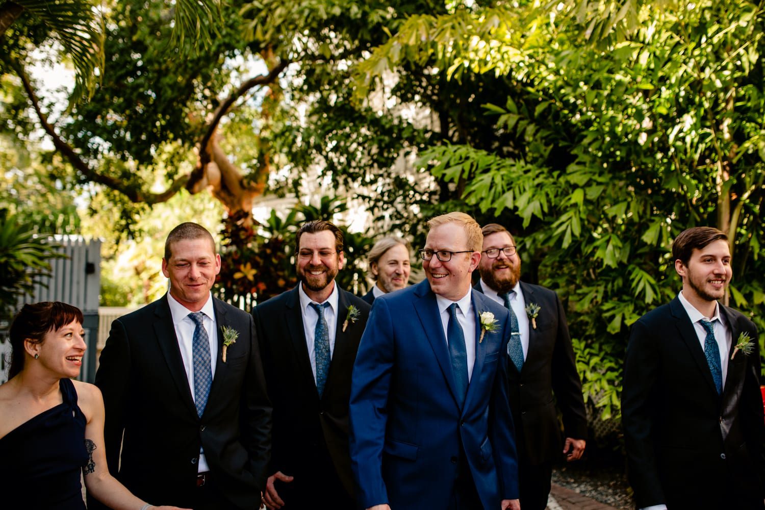 A group of groomsmen walking through a garden at a Fort Zachary Taylor wedding.