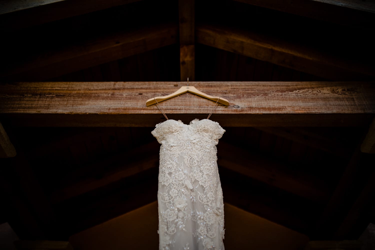 A wedding dress hangs in a barn.
