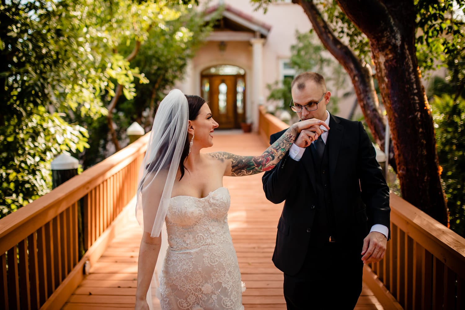 A bride and groom standing on a wooden bridge at a Hemingway home wedding.