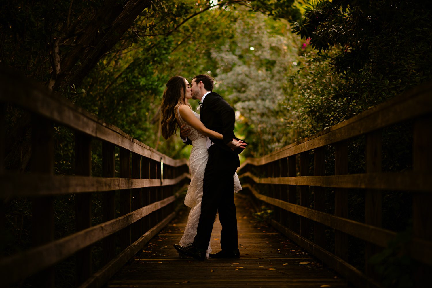 Shana and Patrick kiss on a bridge in the woods during their Hemingway House Wedding.