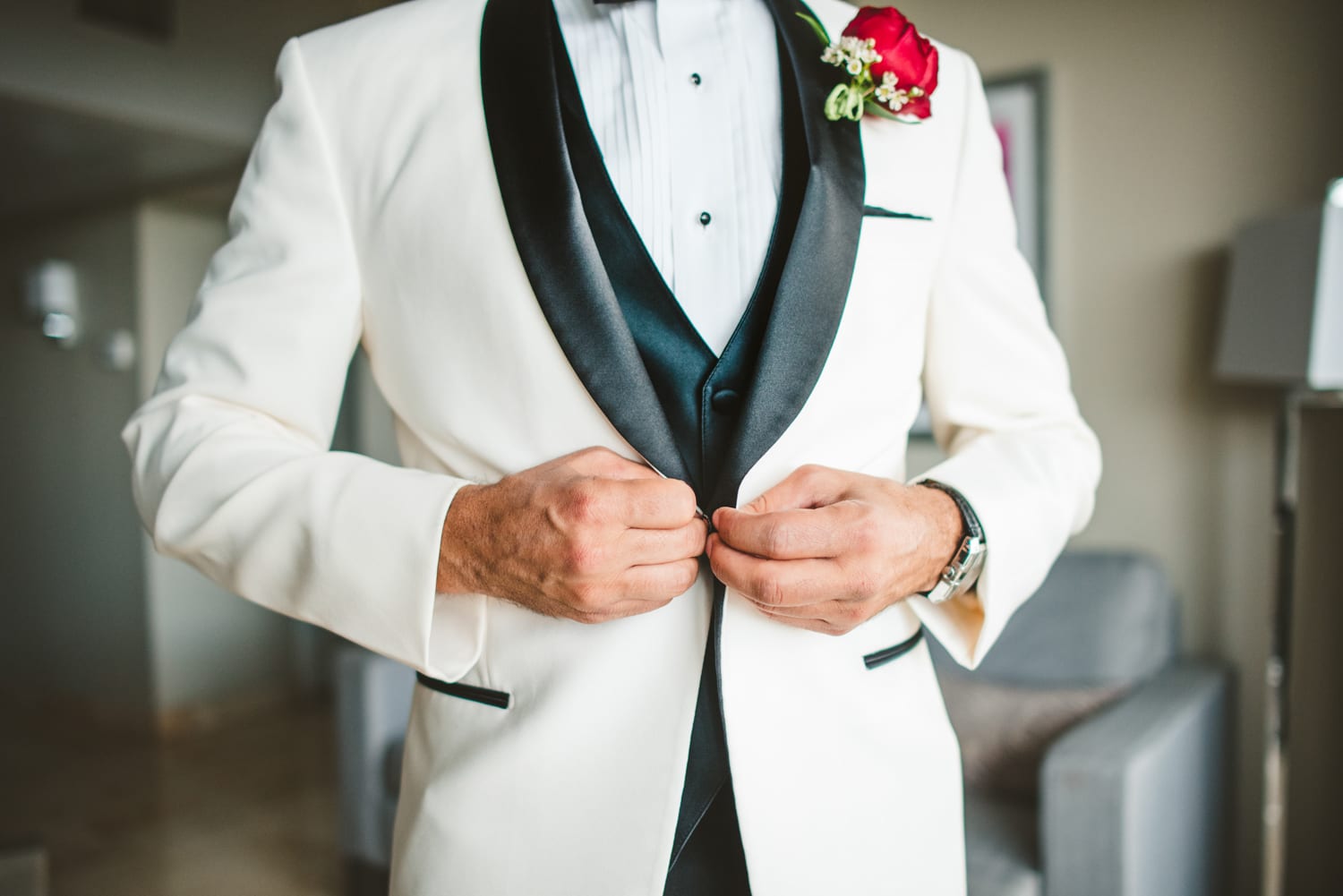 A man in a white tuxedo is adjusting his tie at a Coral Gables wedding.